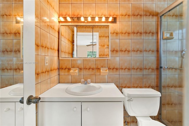 full bath with a shower with door, toilet, tile walls, and vanity