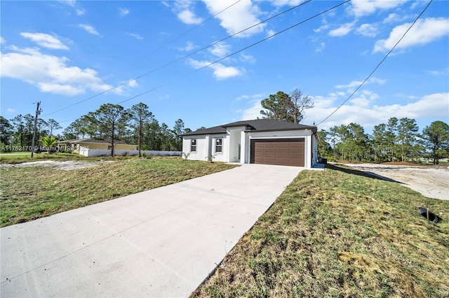 view of front of home featuring stucco siding, a front lawn, concrete driveway, and a garage