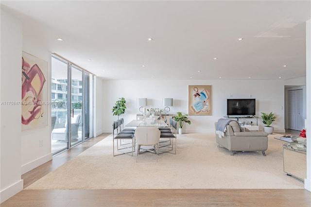 living area with floor to ceiling windows, recessed lighting, baseboards, and light wood finished floors