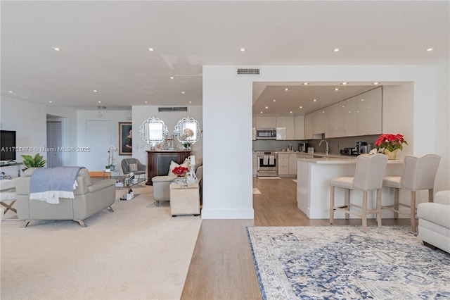 living room with visible vents, recessed lighting, and light wood-type flooring