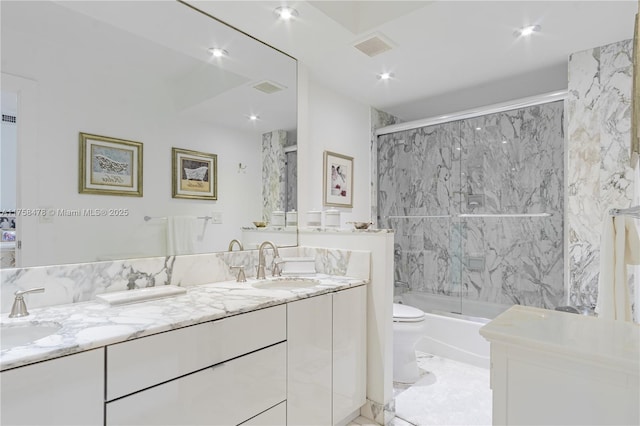 bathroom featuring visible vents, enclosed tub / shower combo, double vanity, a sink, and toilet