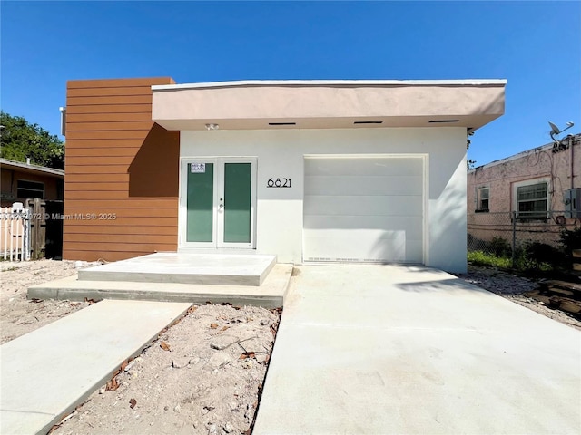 view of front facade with french doors, stucco siding, and fence