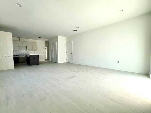 unfurnished living room with recessed lighting, visible vents, light wood-type flooring, and baseboards
