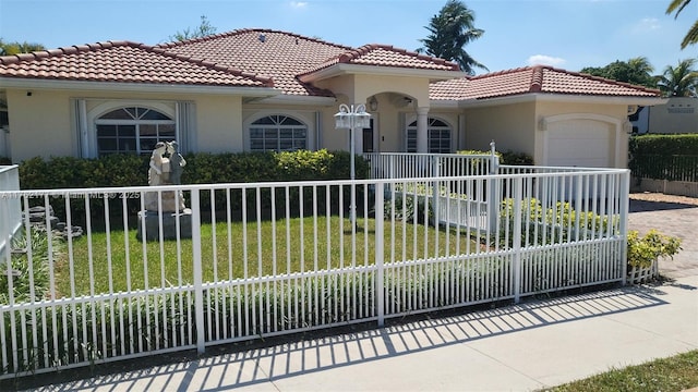 mediterranean / spanish home featuring a fenced front yard, a garage, driveway, and stucco siding