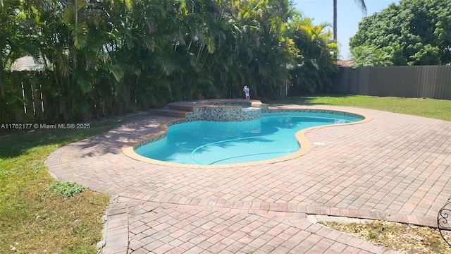 view of swimming pool featuring a patio area, a yard, a pool with connected hot tub, and a fenced backyard