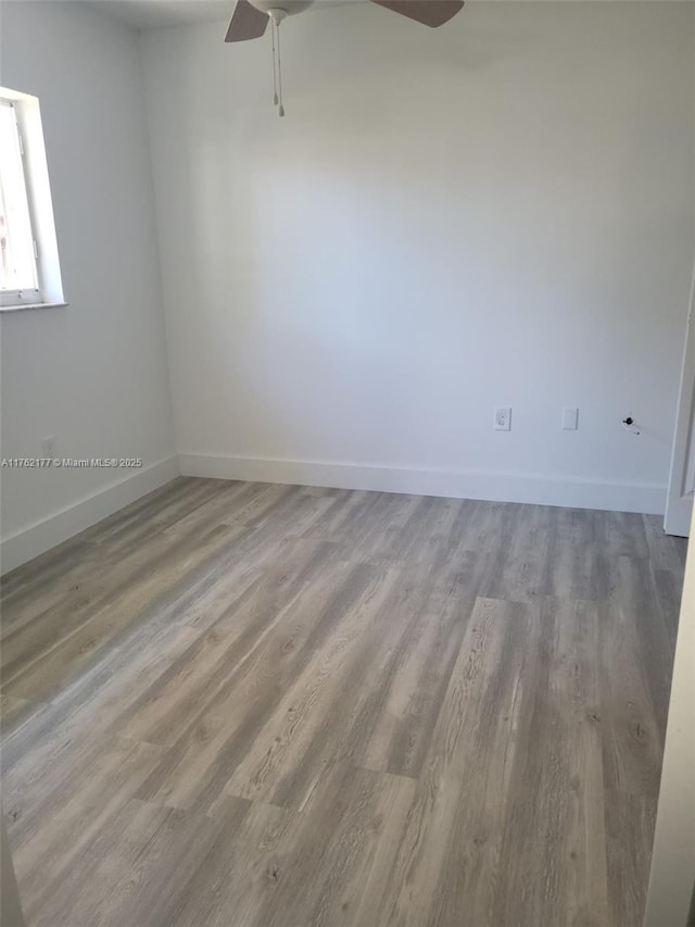 unfurnished room featuring a ceiling fan, wood finished floors, and baseboards