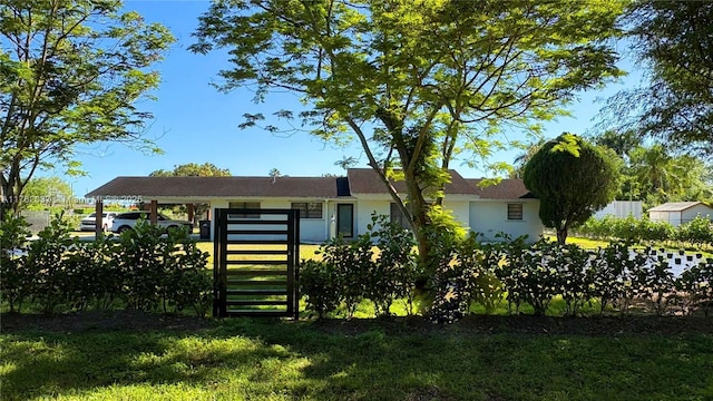 view of front of home with stucco siding, a carport, and fence