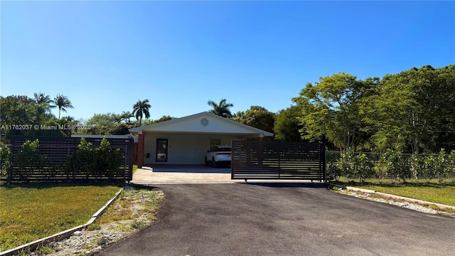 ranch-style home featuring aphalt driveway, fence, a front yard, and a carport