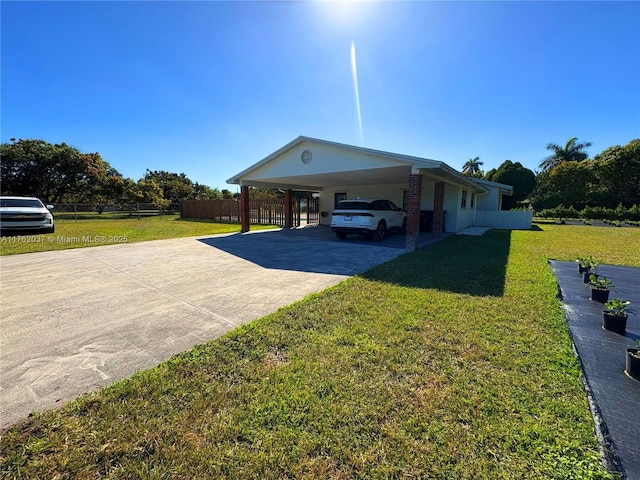 view of side of property with fence, a yard, concrete driveway, an attached carport, and brick siding