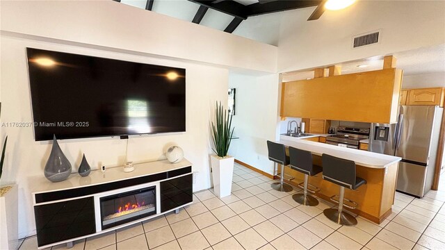 kitchen with visible vents, light countertops, a glass covered fireplace, stainless steel appliances, and a sink