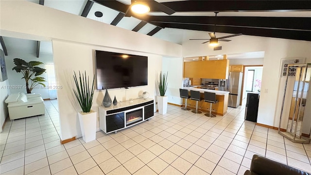 kitchen with a glass covered fireplace, freestanding refrigerator, light tile patterned flooring, light countertops, and vaulted ceiling with beams