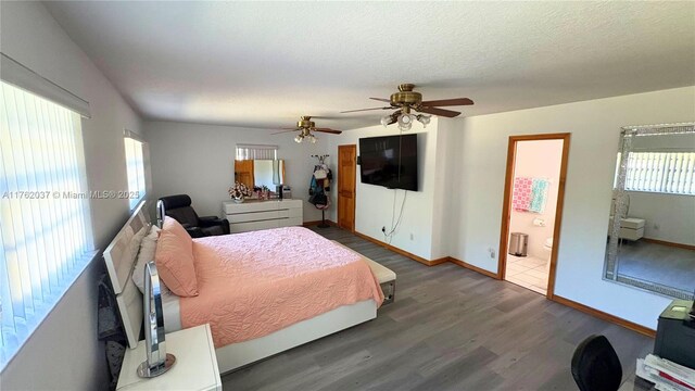 bedroom with multiple windows, wood finished floors, baseboards, and a textured ceiling