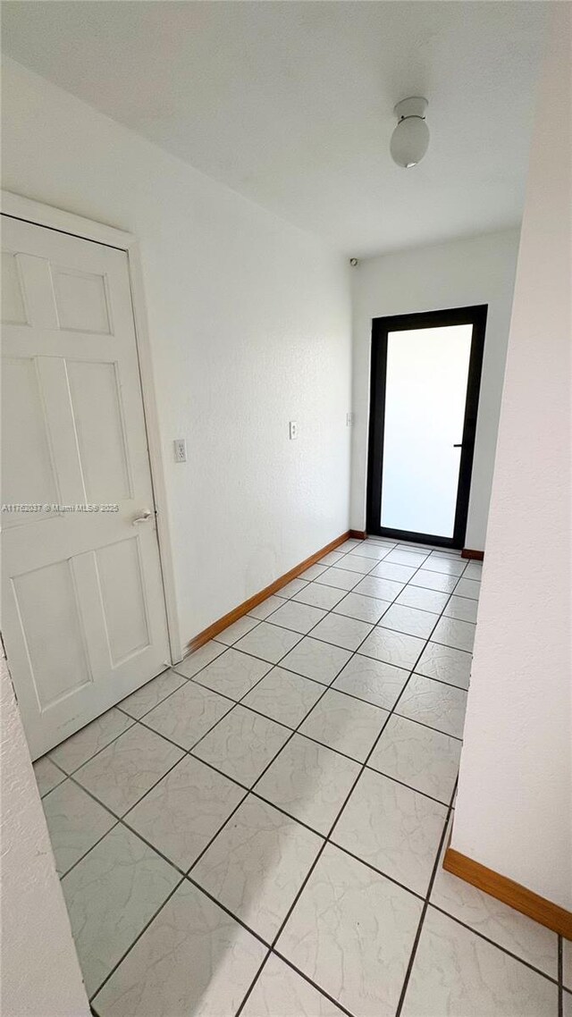 unfurnished room with light tile patterned floors and baseboards