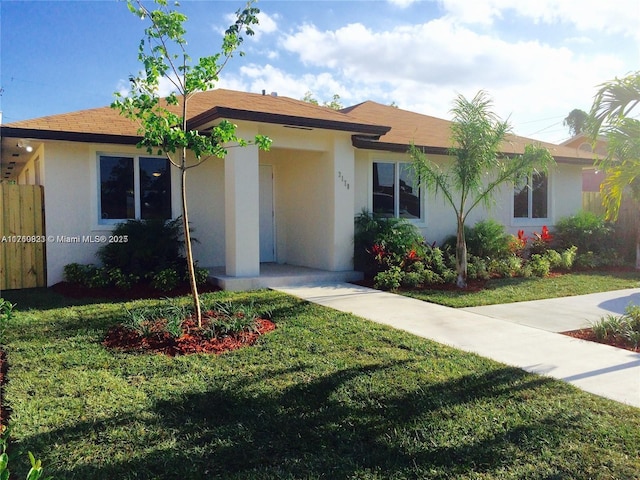 ranch-style house featuring stucco siding, a front lawn, and fence