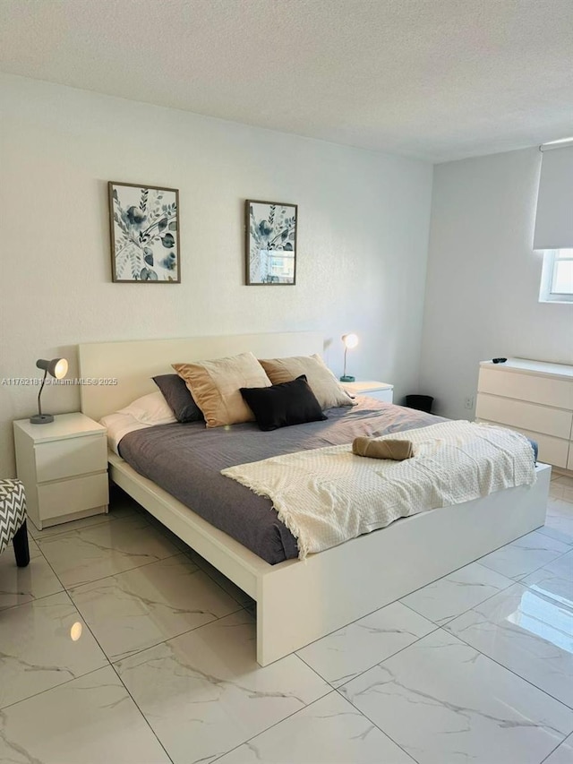 bedroom with marble finish floor and a textured ceiling