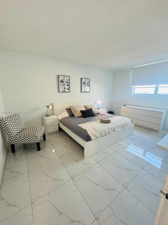 bedroom featuring marble finish floor and a textured ceiling