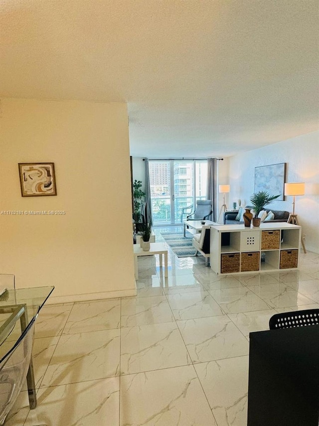 hallway with expansive windows, a textured ceiling, and marble finish floor