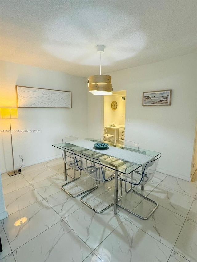 dining space with marble finish floor, a textured ceiling, and baseboards