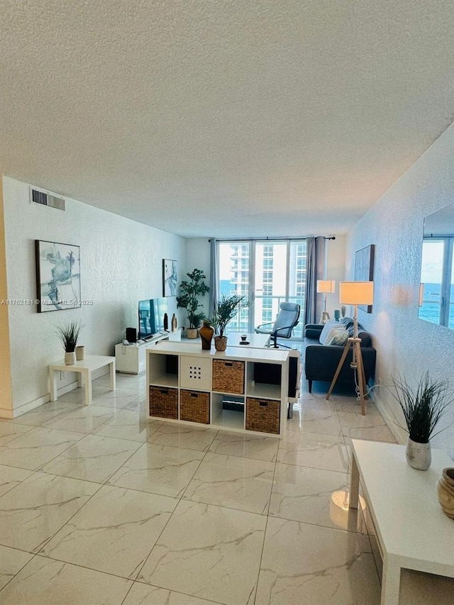 living area featuring marble finish floor, a textured ceiling, and a textured wall