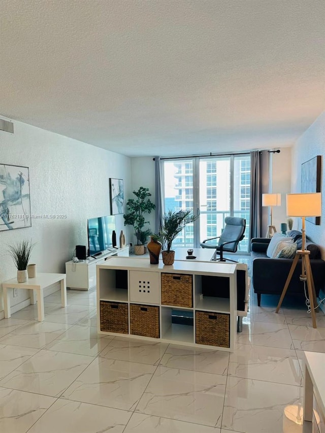 living room featuring visible vents, a textured wall, marble finish floor, and a textured ceiling