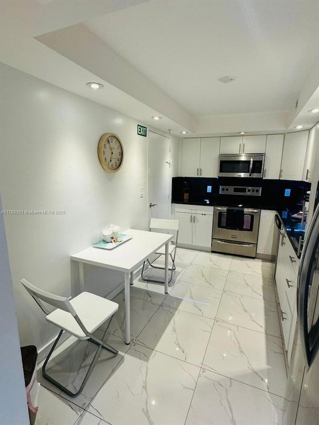 kitchen featuring marble finish floor, dark countertops, recessed lighting, stainless steel appliances, and white cabinets