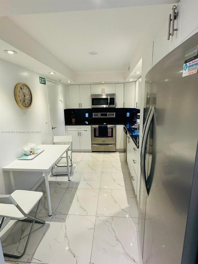 kitchen featuring recessed lighting, marble finish floor, appliances with stainless steel finishes, and white cabinetry