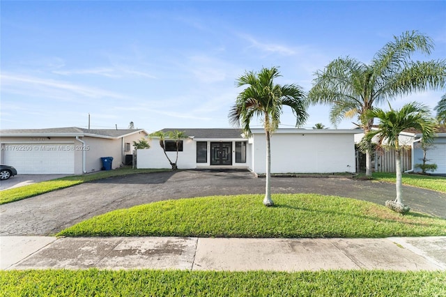 single story home with a front lawn, a garage, driveway, and stucco siding