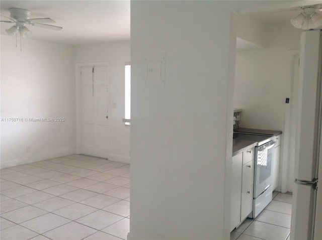 interior space with light tile patterned flooring, a ceiling fan, baseboards, and a healthy amount of sunlight