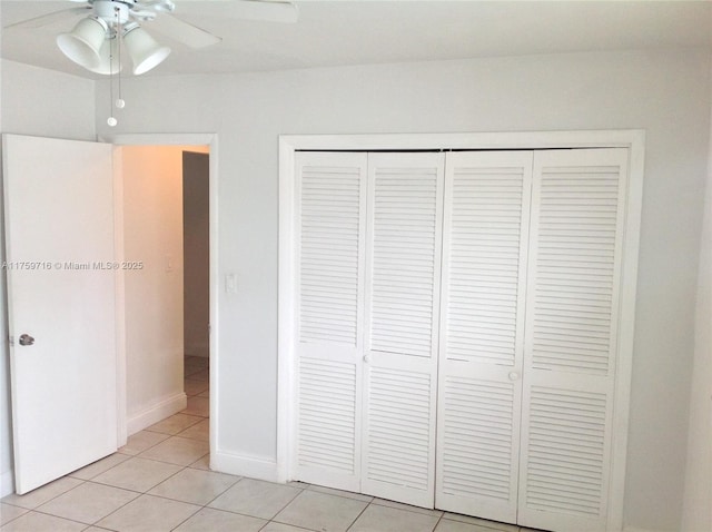 unfurnished bedroom with a closet, light tile patterned floors, ceiling fan, and baseboards