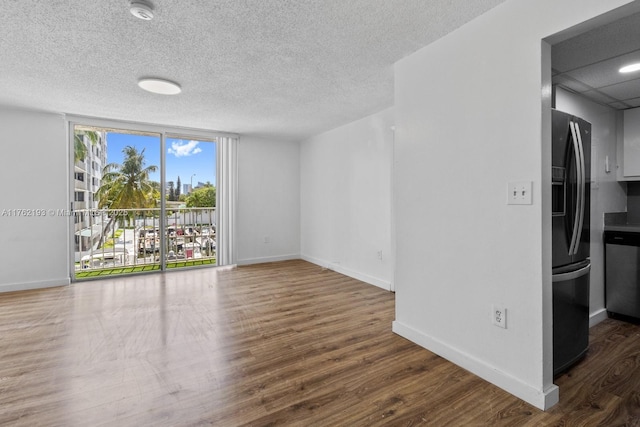 unfurnished room featuring floor to ceiling windows, wood finished floors, baseboards, and a textured ceiling