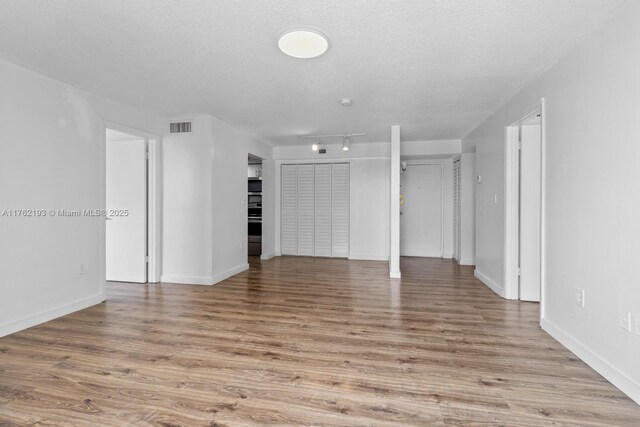 unfurnished living room with baseboards, visible vents, a textured ceiling, and light wood-style floors