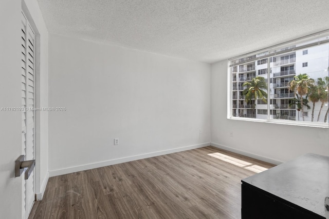 interior space featuring wood finished floors, baseboards, and a textured ceiling