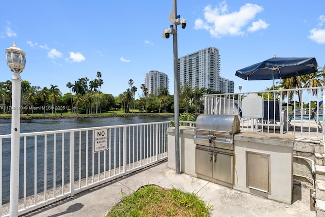 view of patio featuring a city view, exterior kitchen, a water view, and grilling area