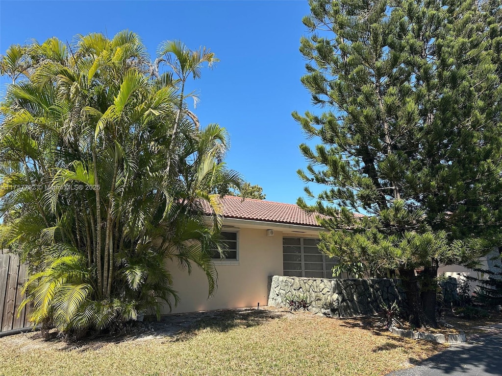 view of home's exterior with stucco siding, a tiled roof, and fence