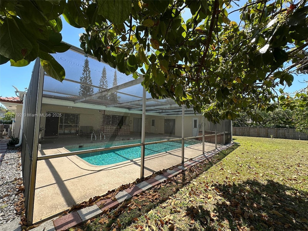 view of swimming pool featuring a patio, fence, a yard, a fenced in pool, and a lanai