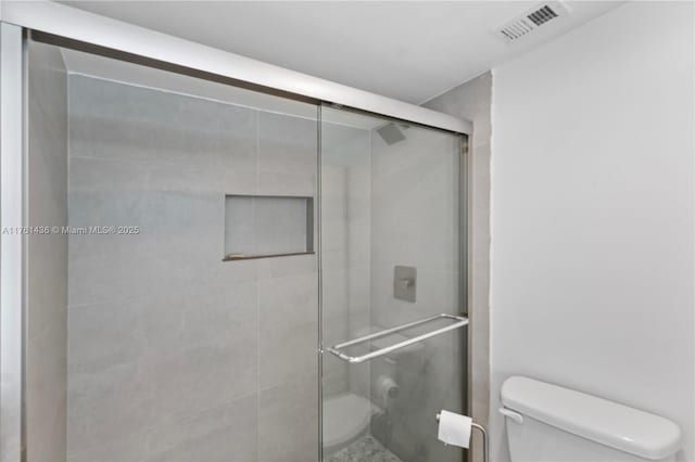 full bathroom with a shower stall, toilet, and visible vents