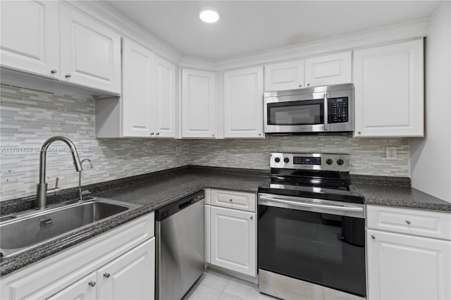 kitchen featuring a sink, dark countertops, appliances with stainless steel finishes, and white cabinets