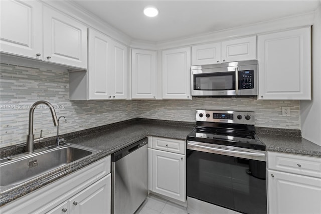 kitchen featuring dark countertops, white cabinets, appliances with stainless steel finishes, and a sink