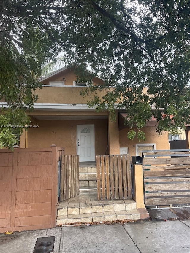 view of front of property featuring stucco siding, a fenced front yard, and a gate