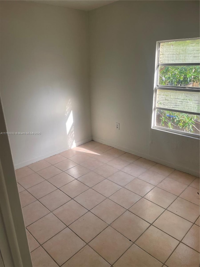 unfurnished room featuring baseboards and light tile patterned flooring