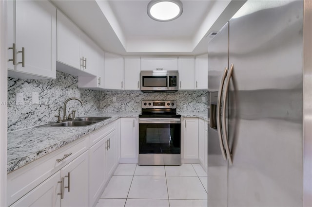 kitchen featuring a sink, backsplash, stainless steel appliances, light tile patterned flooring, and a raised ceiling