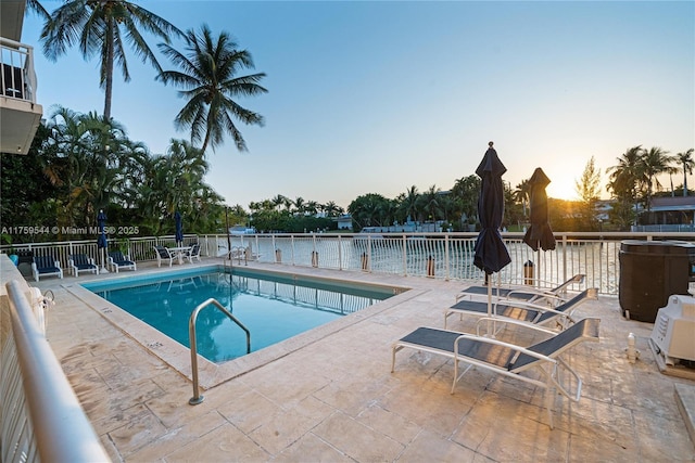 pool at dusk with a community pool, a patio, and fence