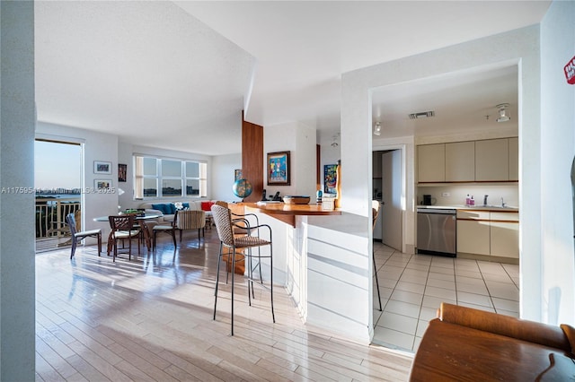 kitchen with visible vents, stainless steel dishwasher, open floor plan, and light wood-style flooring