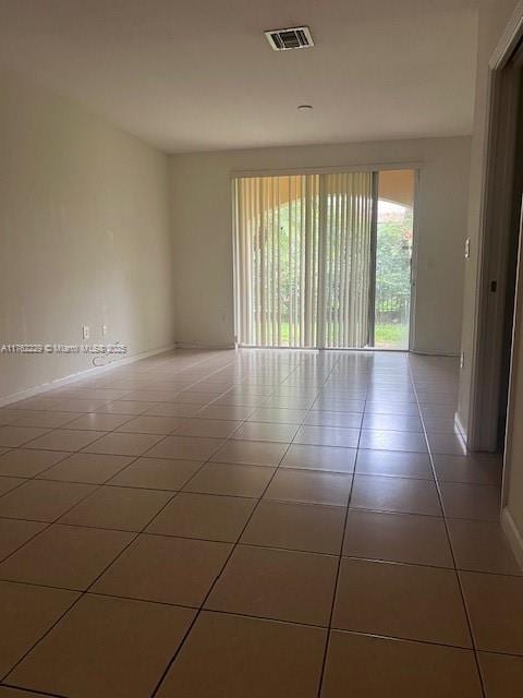 tiled empty room featuring visible vents and baseboards