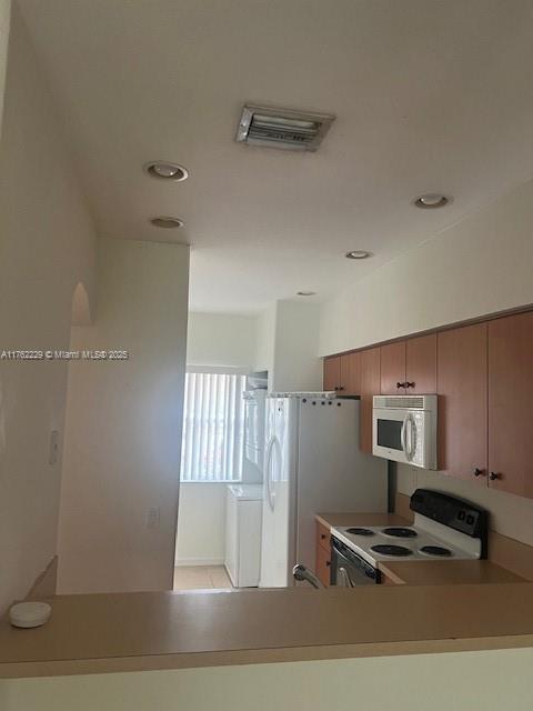 kitchen with visible vents, brown cabinets, white appliances, and light countertops