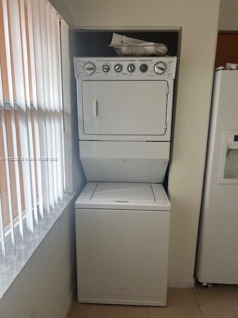 laundry area with laundry area, light tile patterned flooring, and stacked washer / drying machine