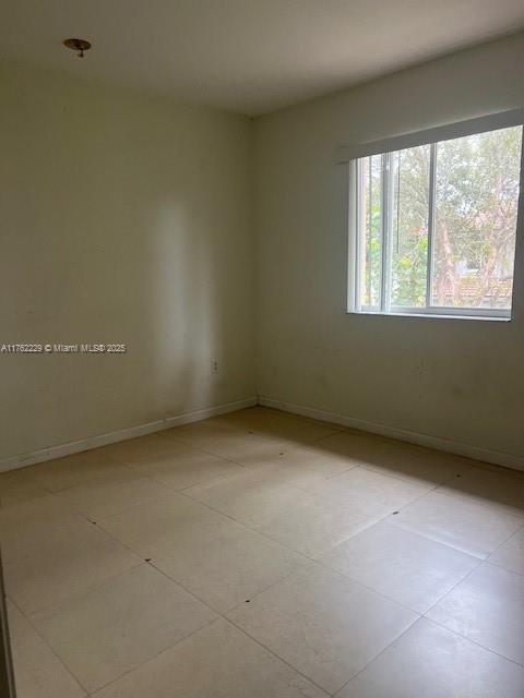 spare room with light tile patterned flooring and baseboards