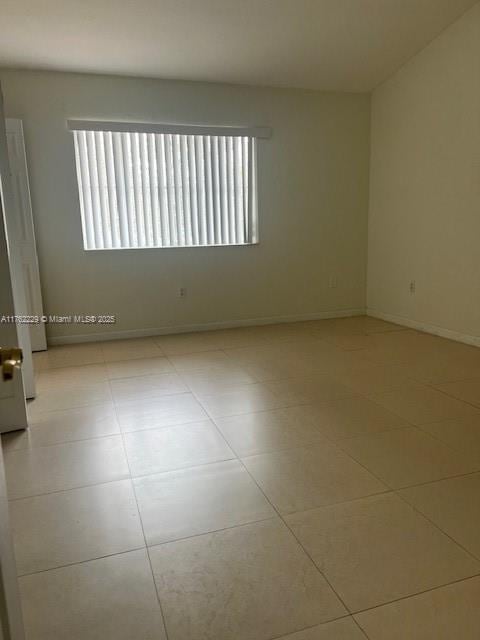 unfurnished room featuring tile patterned floors and baseboards