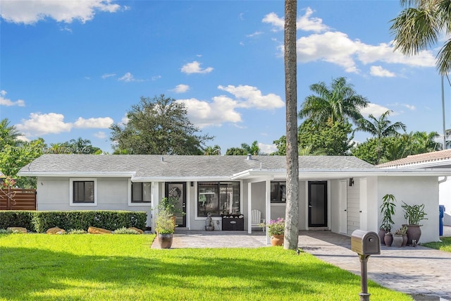 view of front of property featuring a patio, stucco siding, and a front lawn