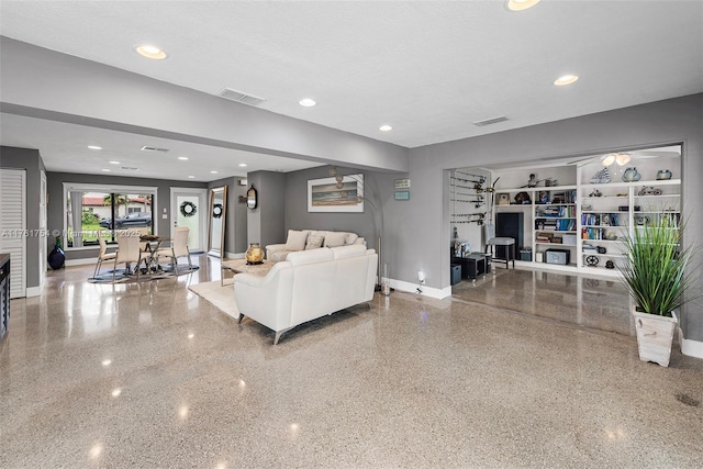 living room with baseboards, visible vents, and speckled floor